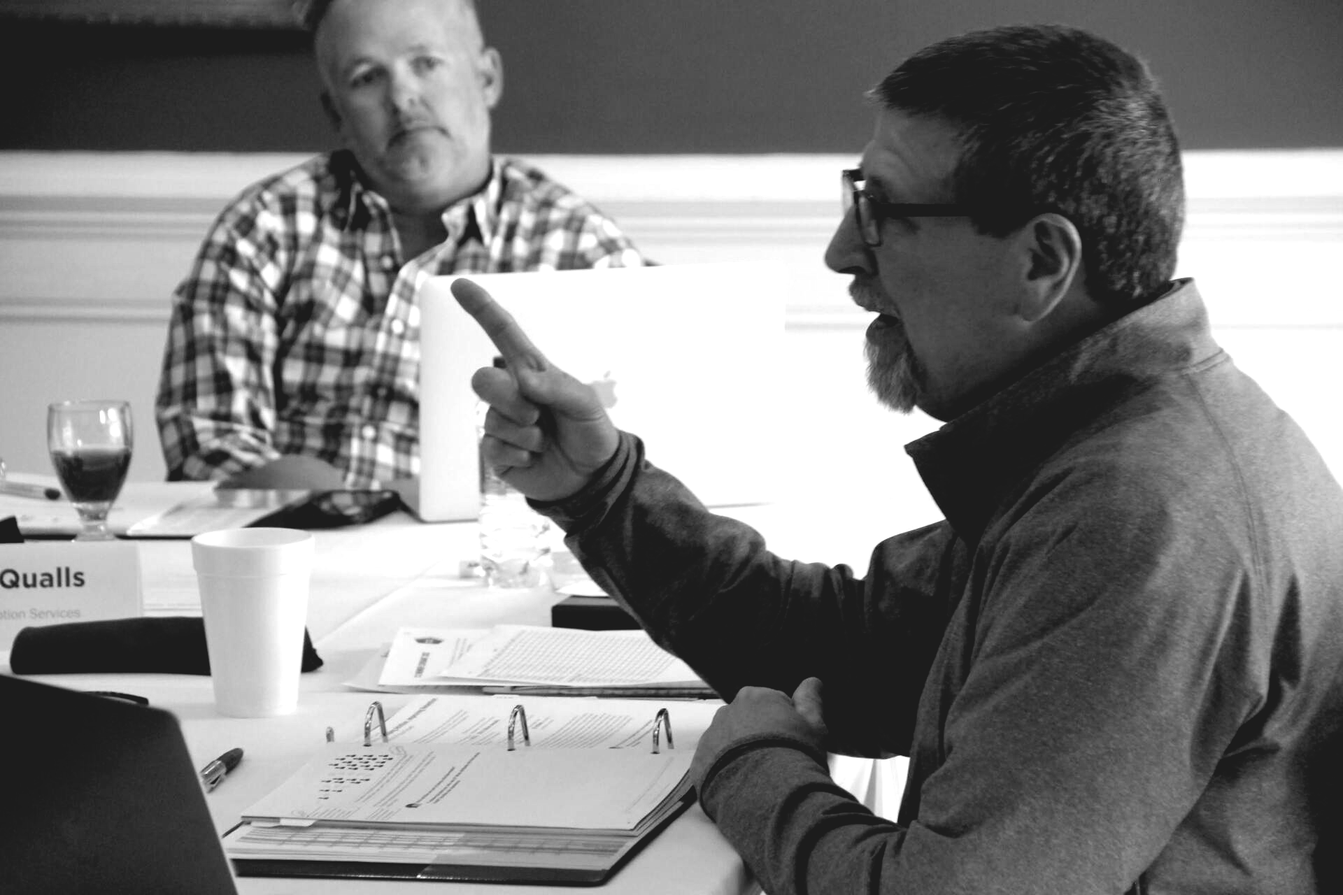 a man is pointing at something while sitting at a table .