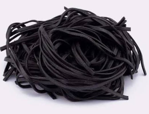 Pasta al nero di seppia, un ammasso aggrovigliato su una superficie bianca.