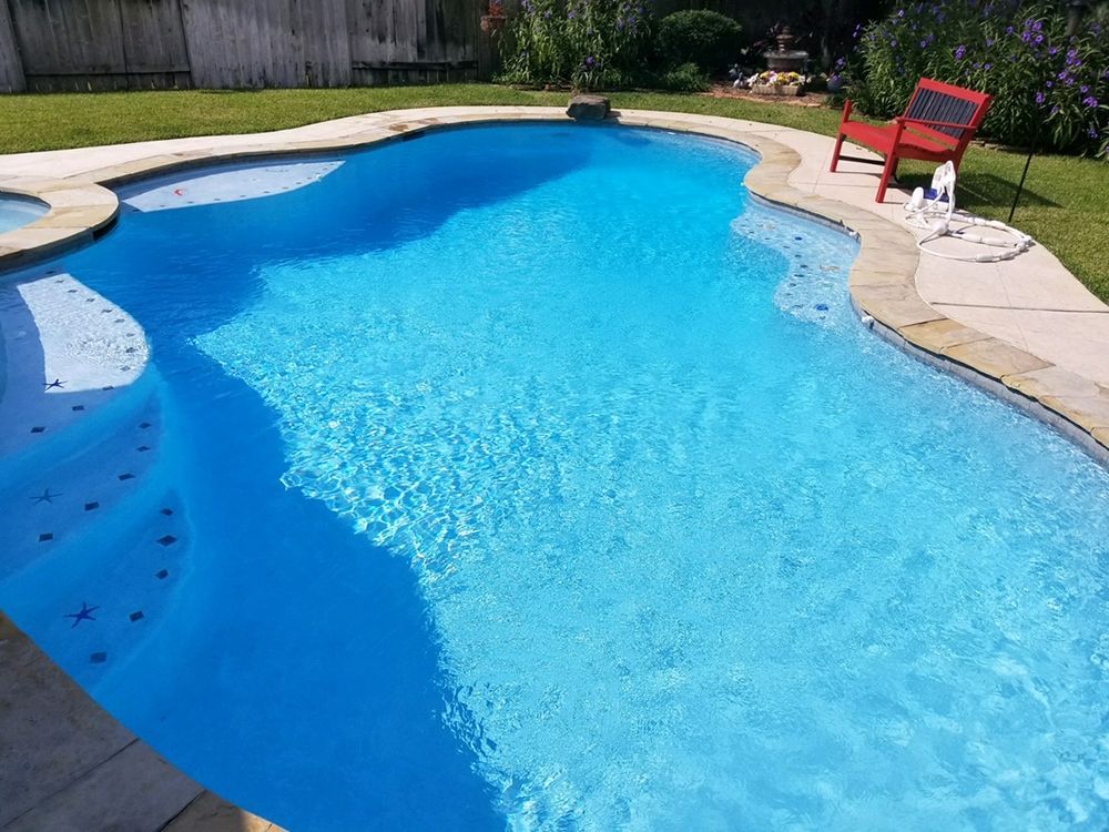 A large swimming pool with a diving board in front of a house