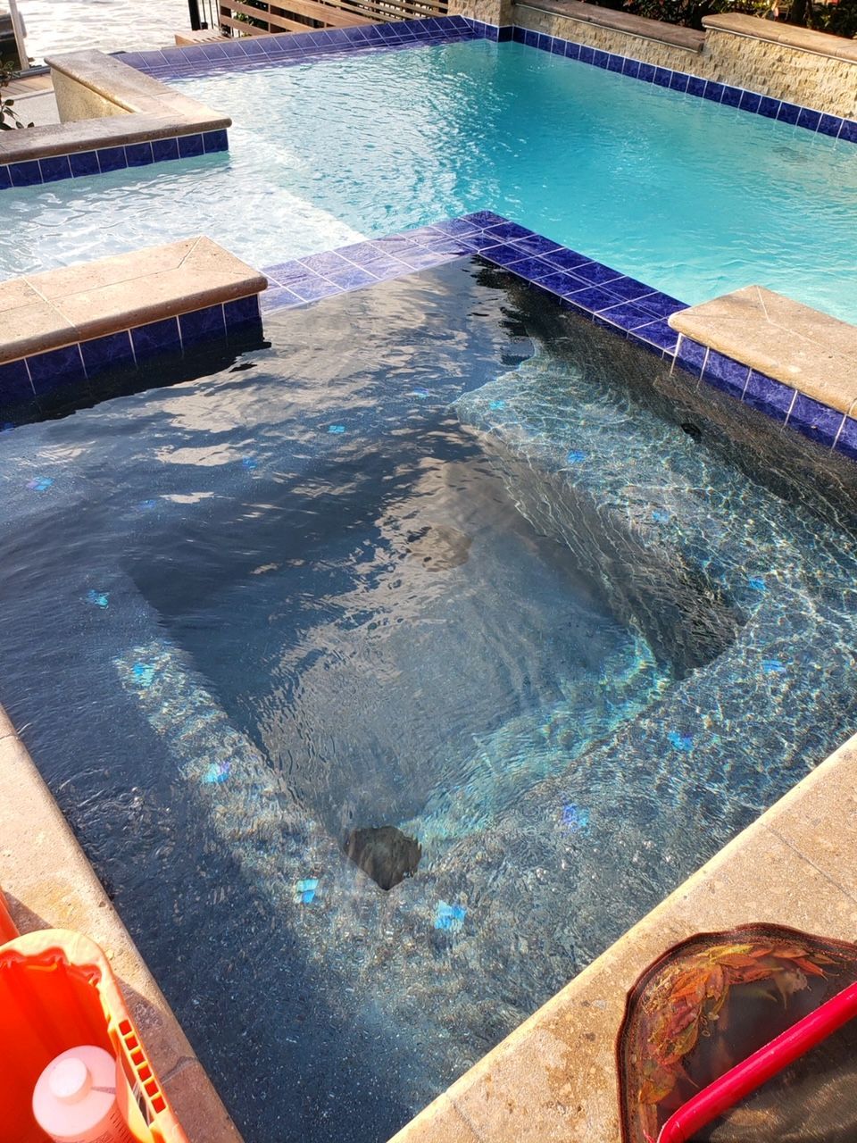 A large swimming pool with a hot tub in the middle of it.