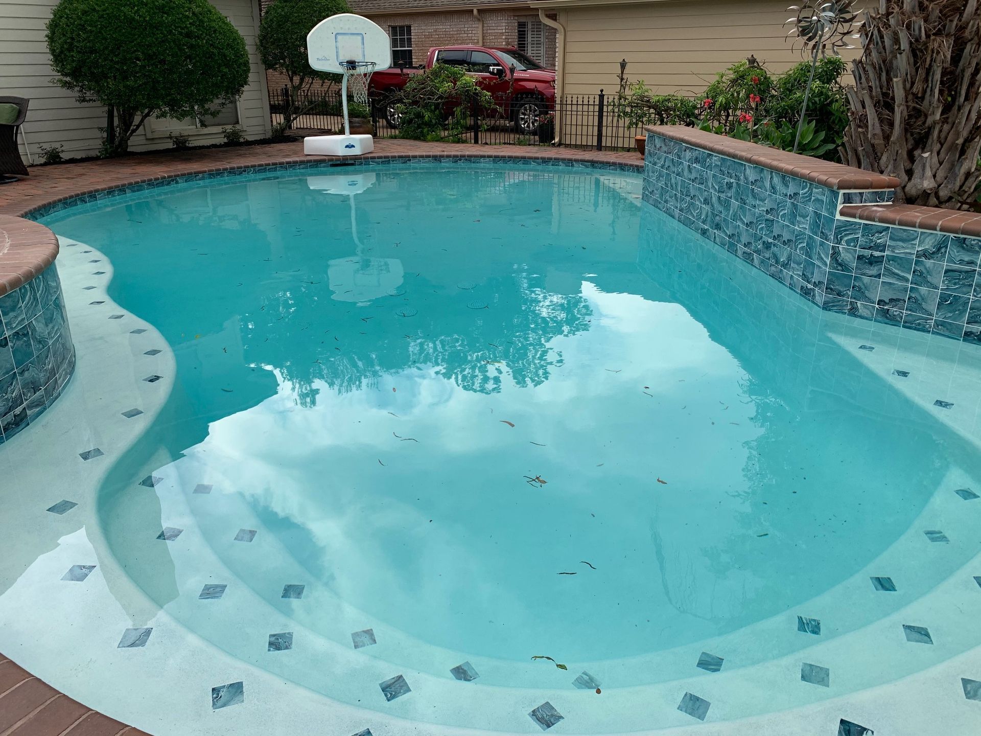 A large swimming pool with a basketball hoop in the background.