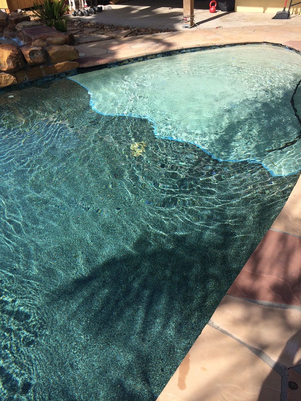 A swimming pool with a hose attached to the side of it.