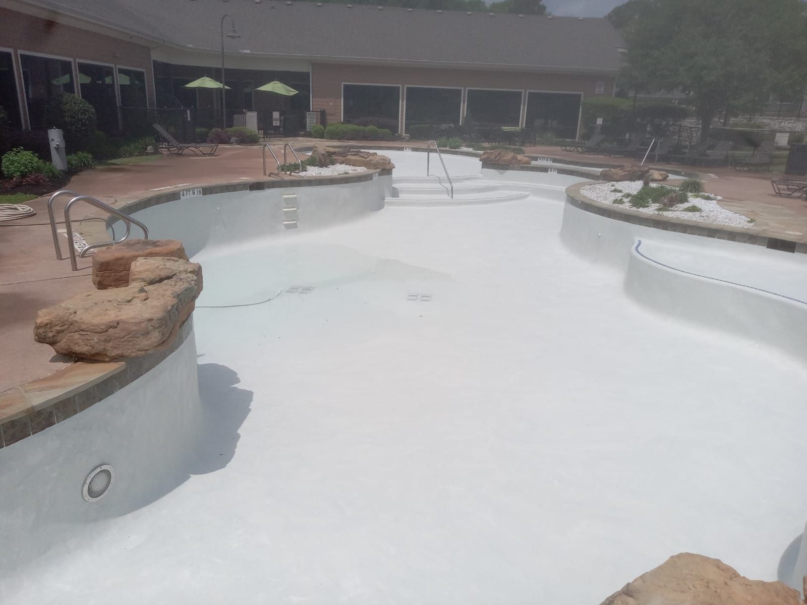 A large white swimming pool with a house in the background.
