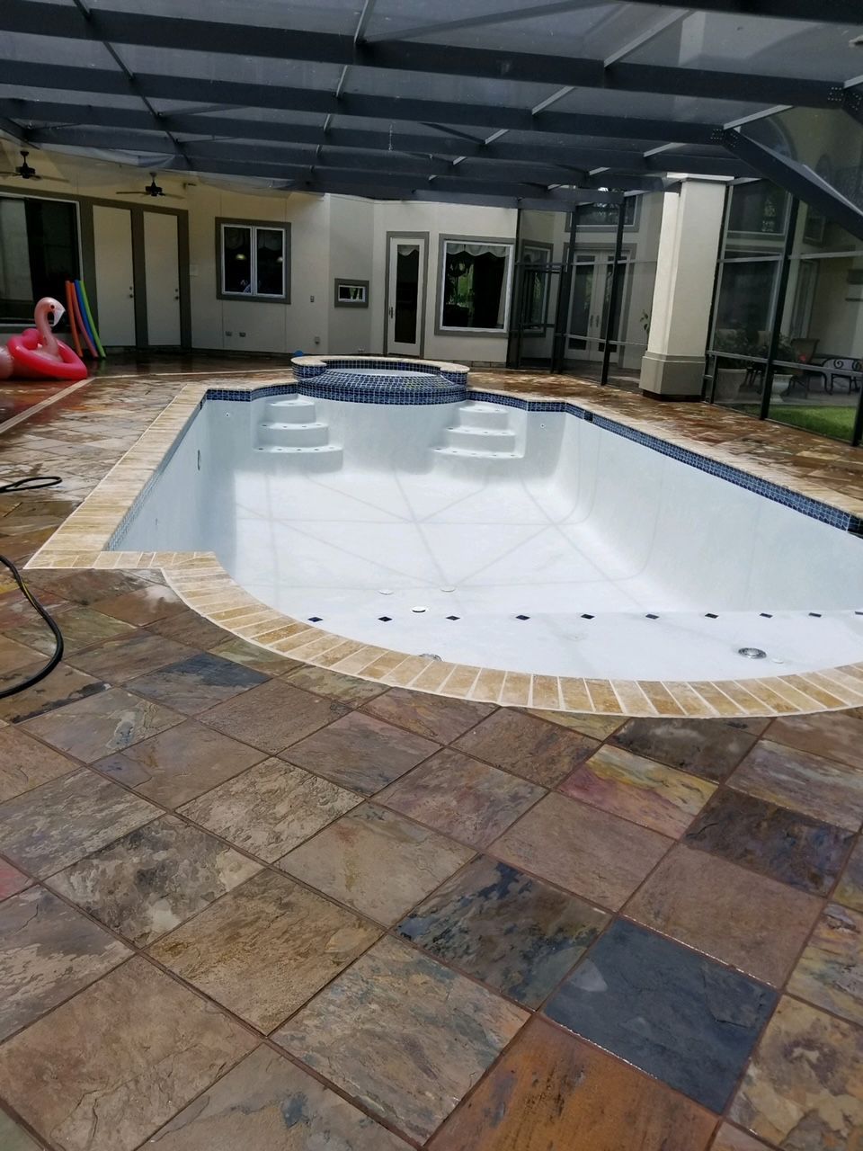 A large swimming pool is sitting on top of a tiled patio.