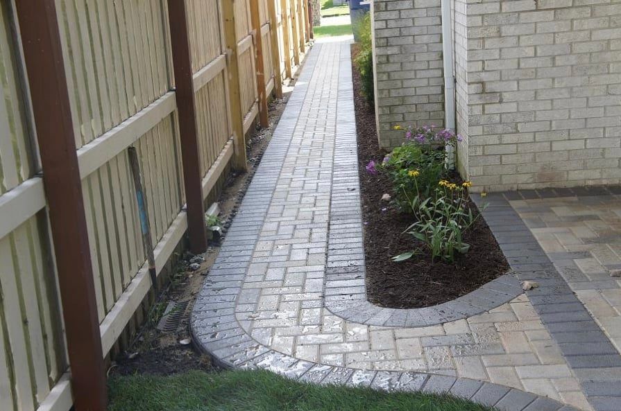 A stone walkway with rocks and a bush in the background.