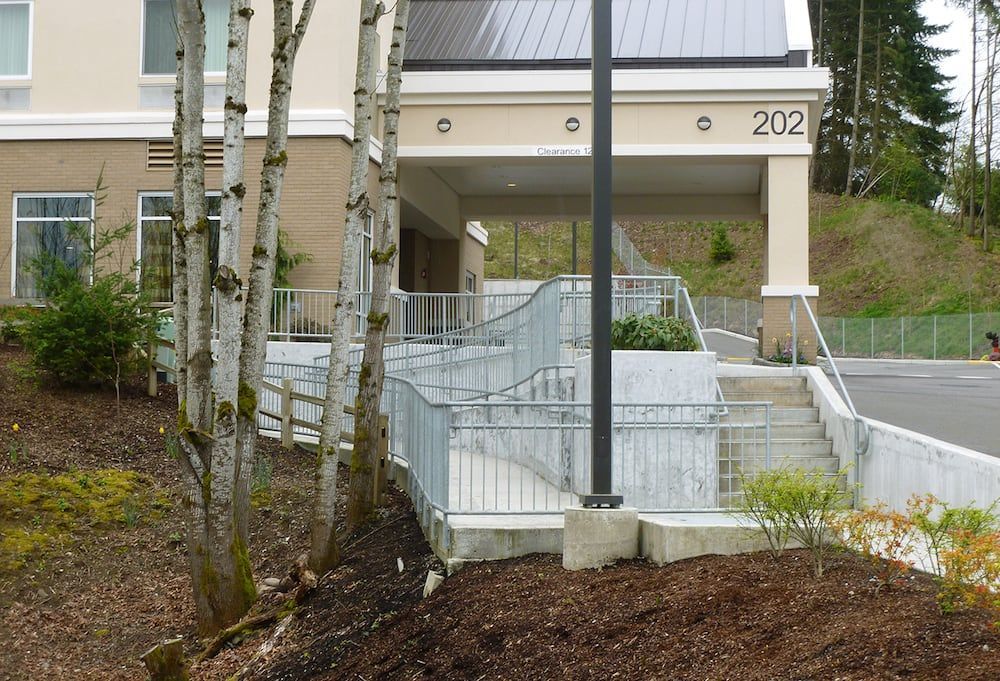 Commercial ADA ramp with custom welded steel railing system and concrete walkway