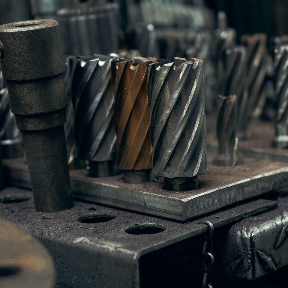 Close-up of metal drill bits and cutting tools on workshop surface