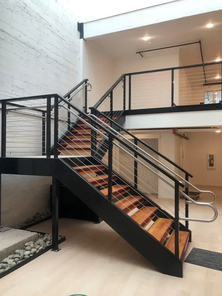 Interior staircase with custom welded steel railing system and wood steps