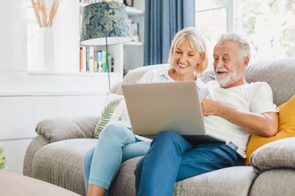 Couple sitting on their couch watching educational videos on a laptop