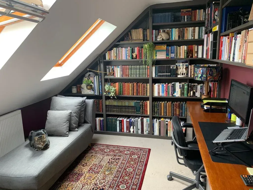 An empty attic with hardwood floors and a skylight.