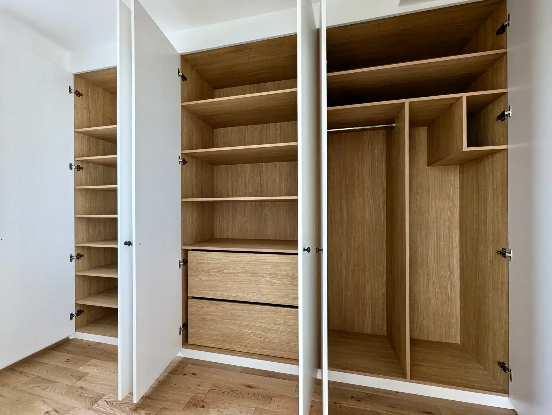 Open white and wood-grain closet with shelves, drawers, and hanging rod, empty inside.