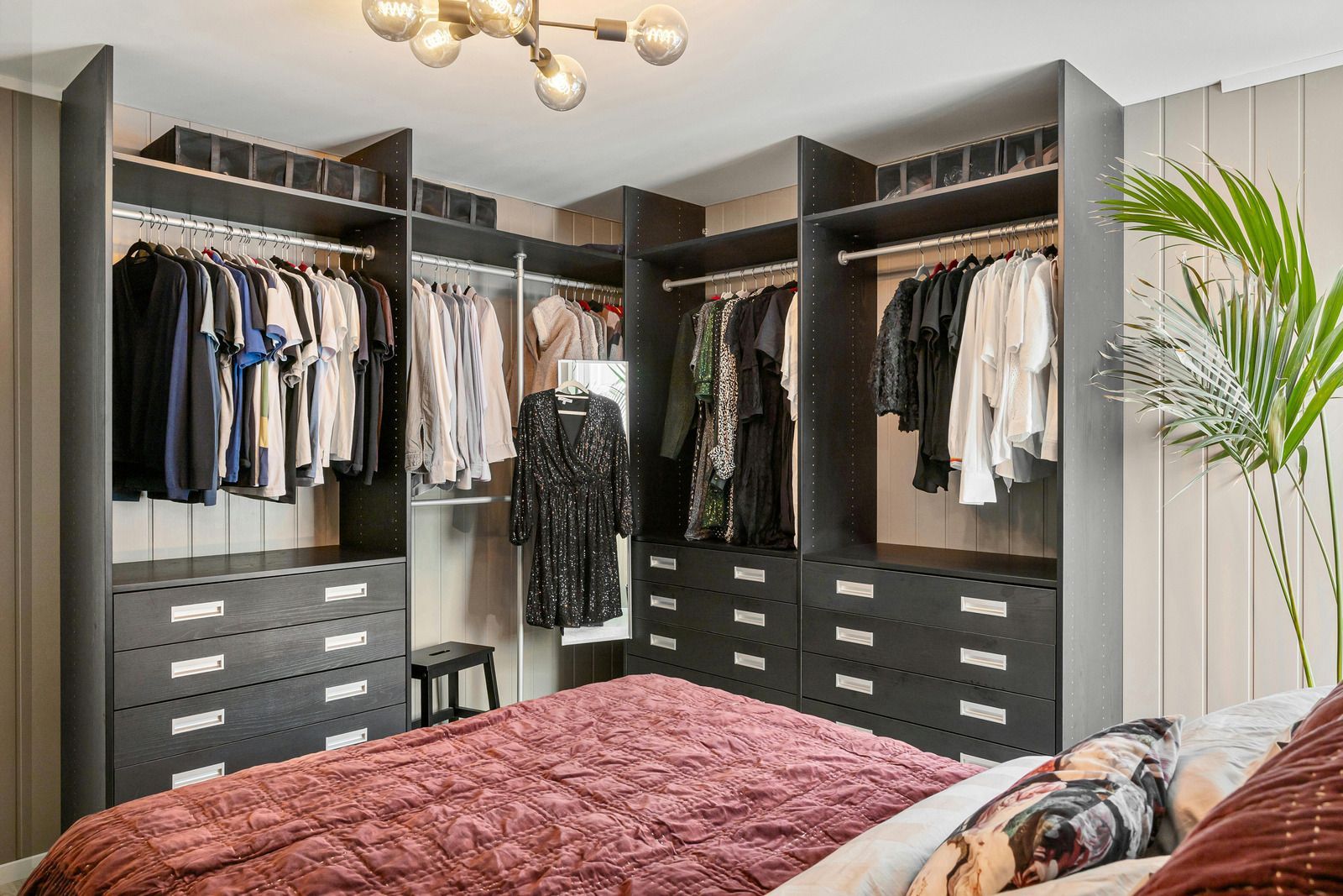 White built-in storage closets with custom-fitted doors following the slope of an attic ceiling in a room with wood floors.