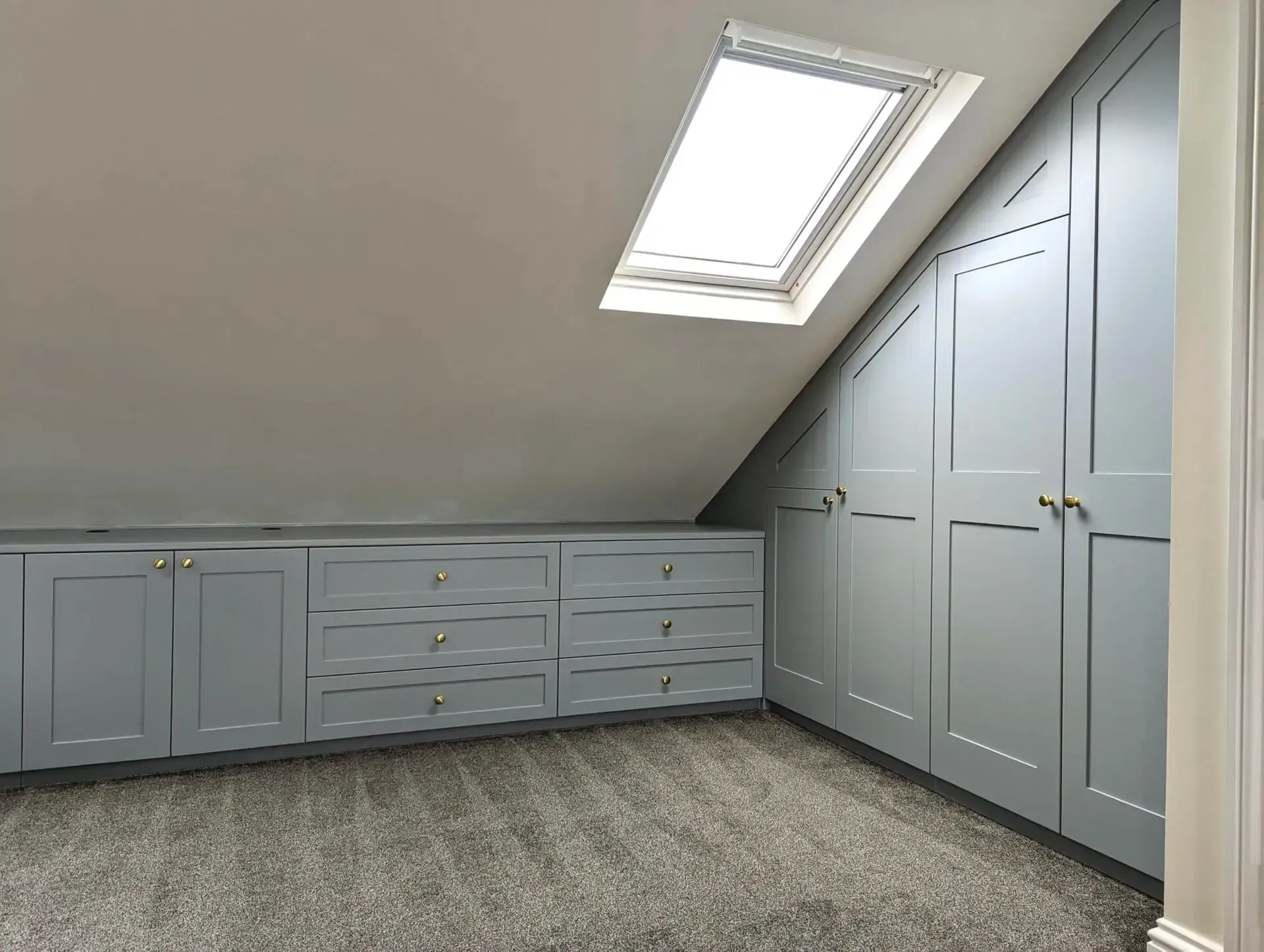 An empty attic with hardwood floors and a skylight.