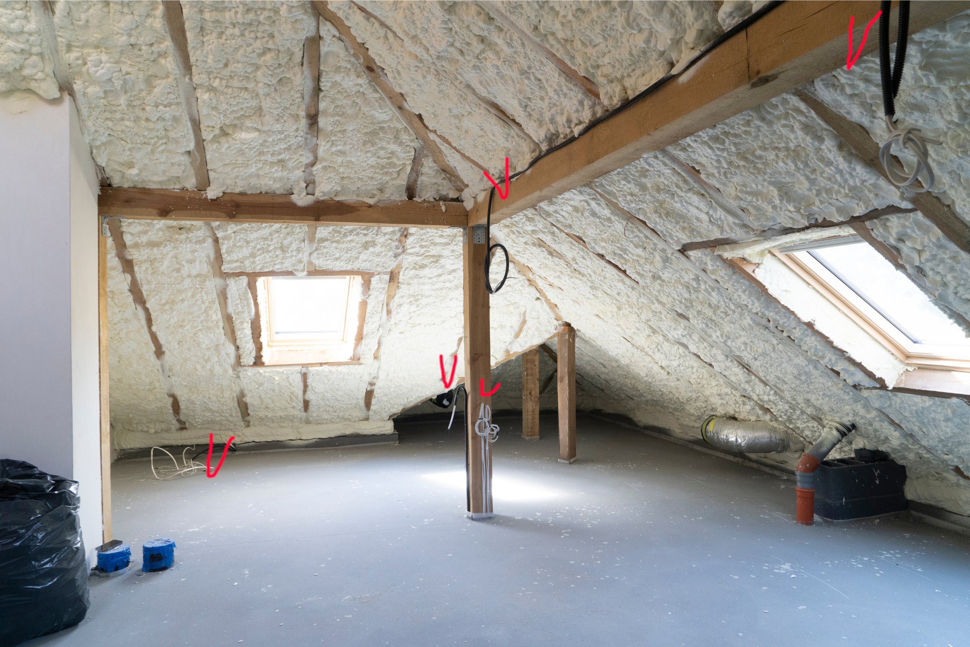 An empty attic with foam insulation and a window.