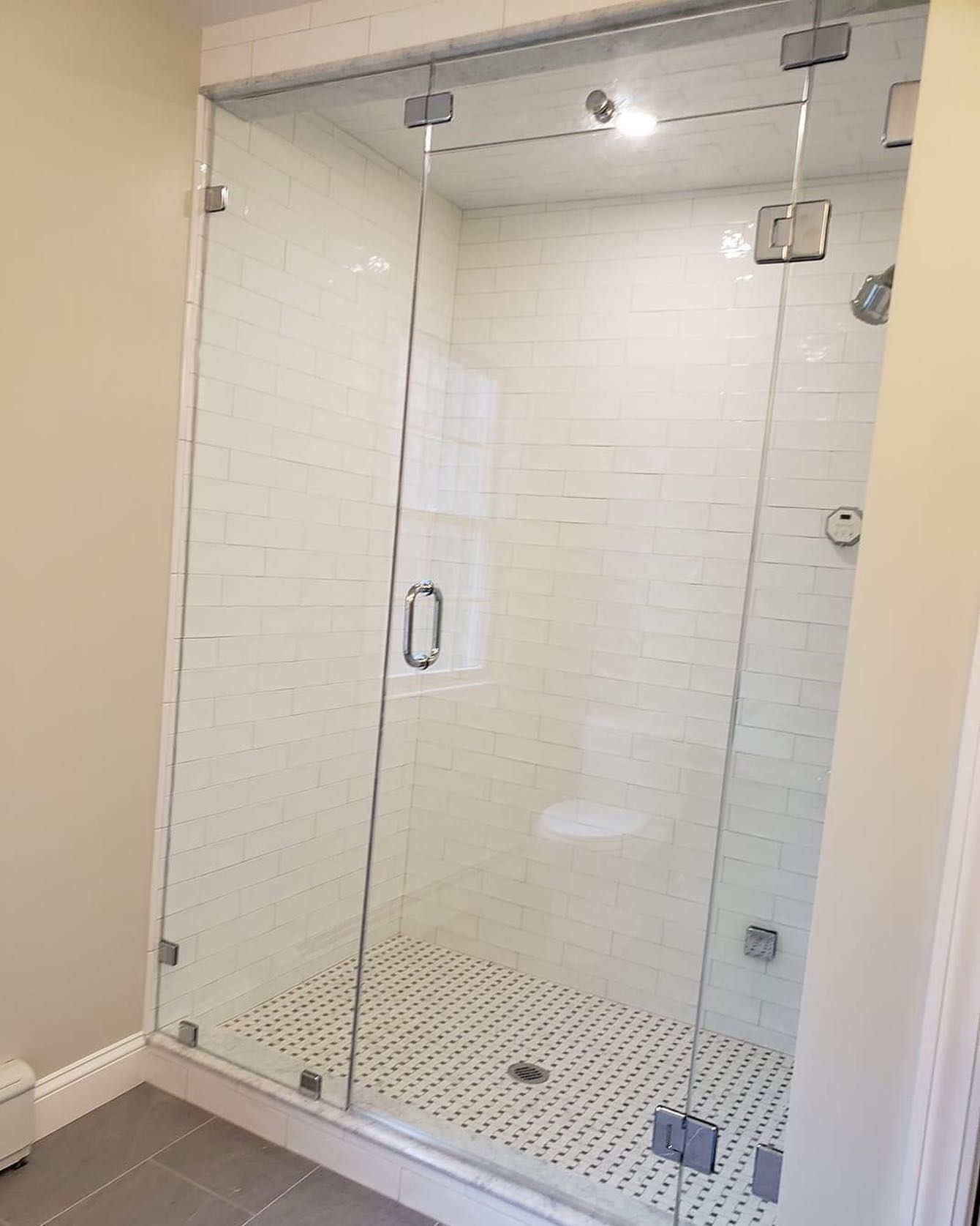 A bathroom with a walk in shower with a glass door.