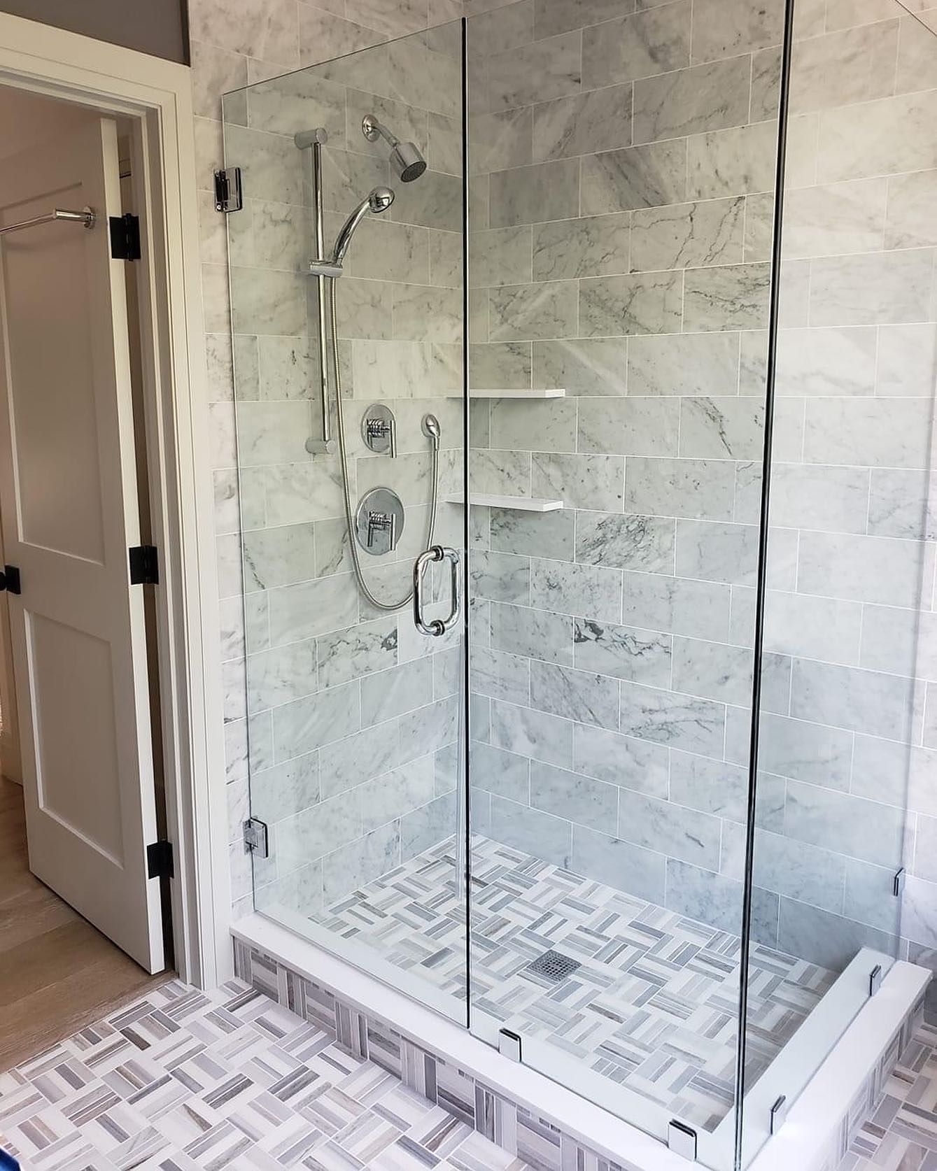 A bathroom with a walk in shower with a glass door