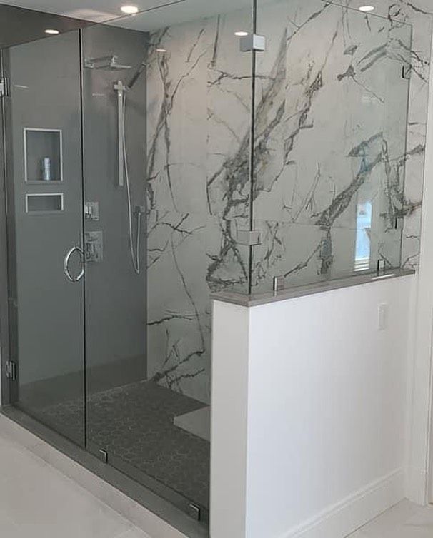 A bathroom with a walk in shower and a marble wall.