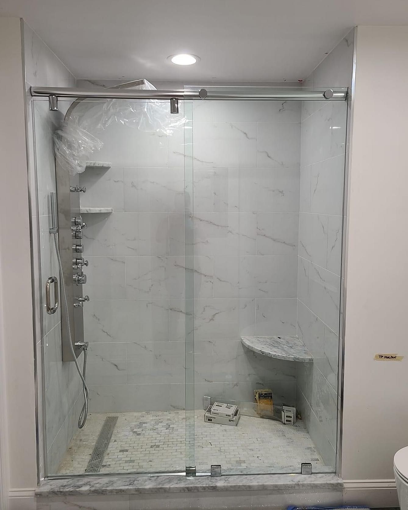 A bathroom with a sliding glass shower door and a toilet.