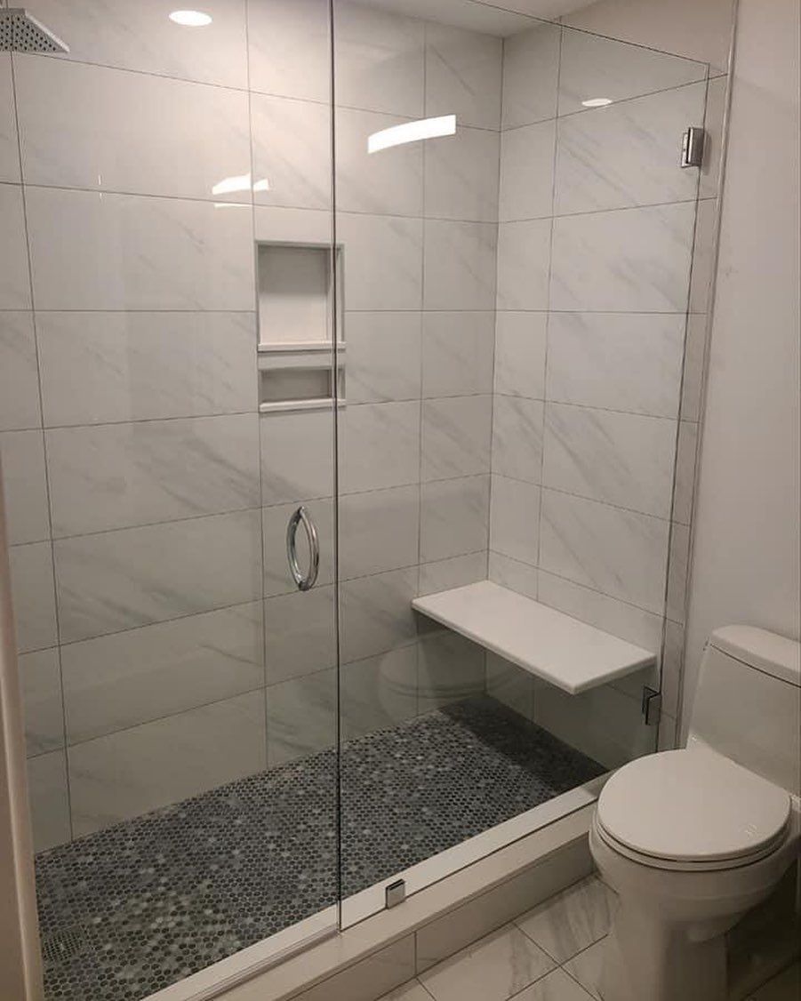 A bathroom with a toilet and a walk in shower with a glass door.