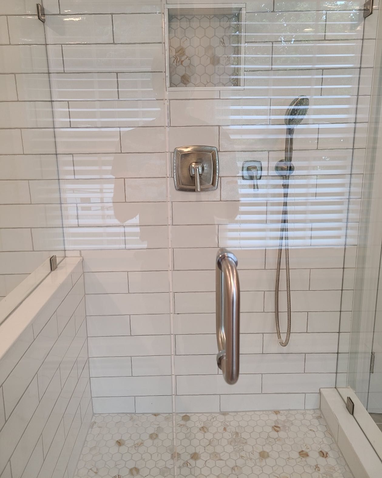 A bathroom with white tiles and a walk in shower