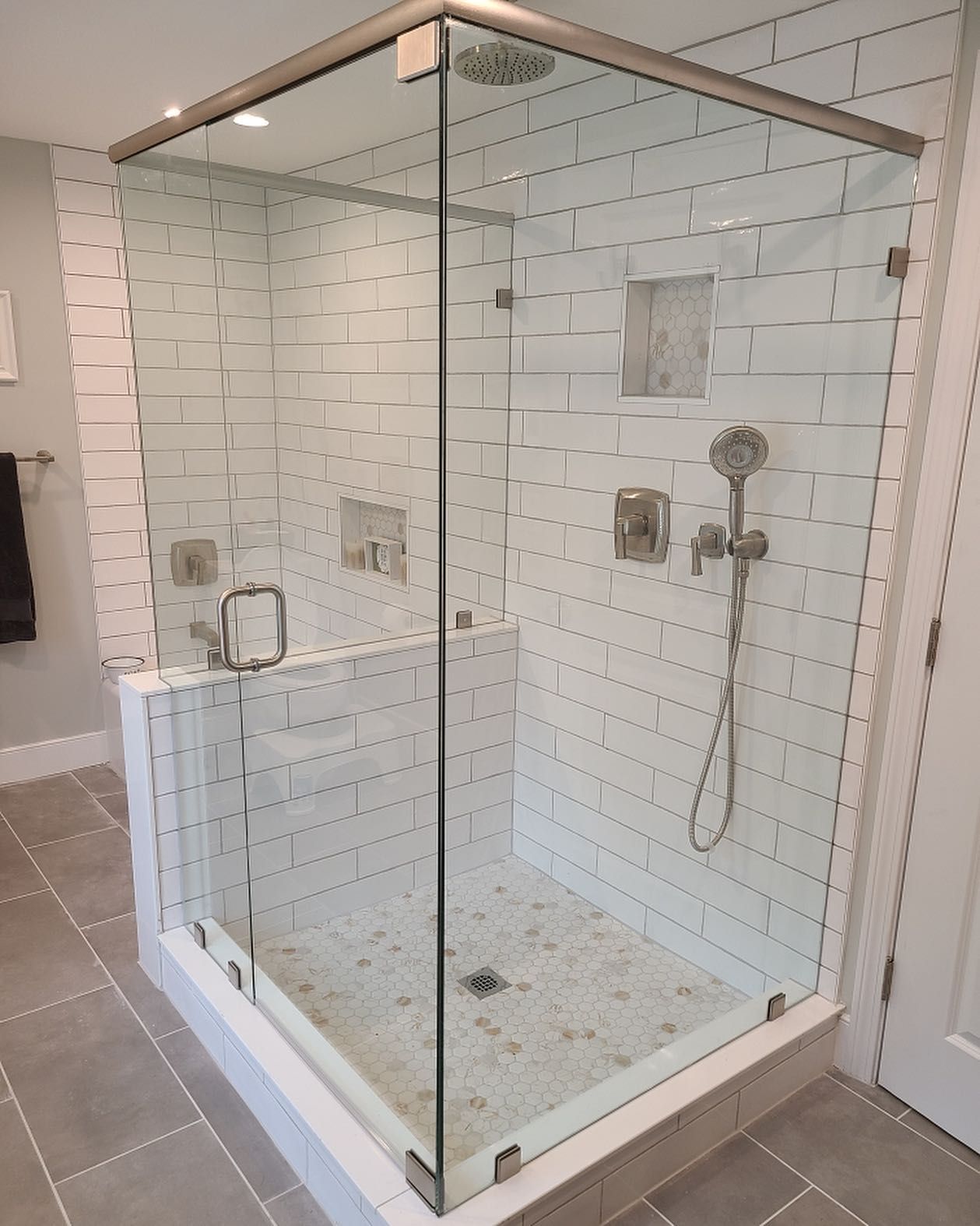A bathroom with a walk in shower with a glass door.