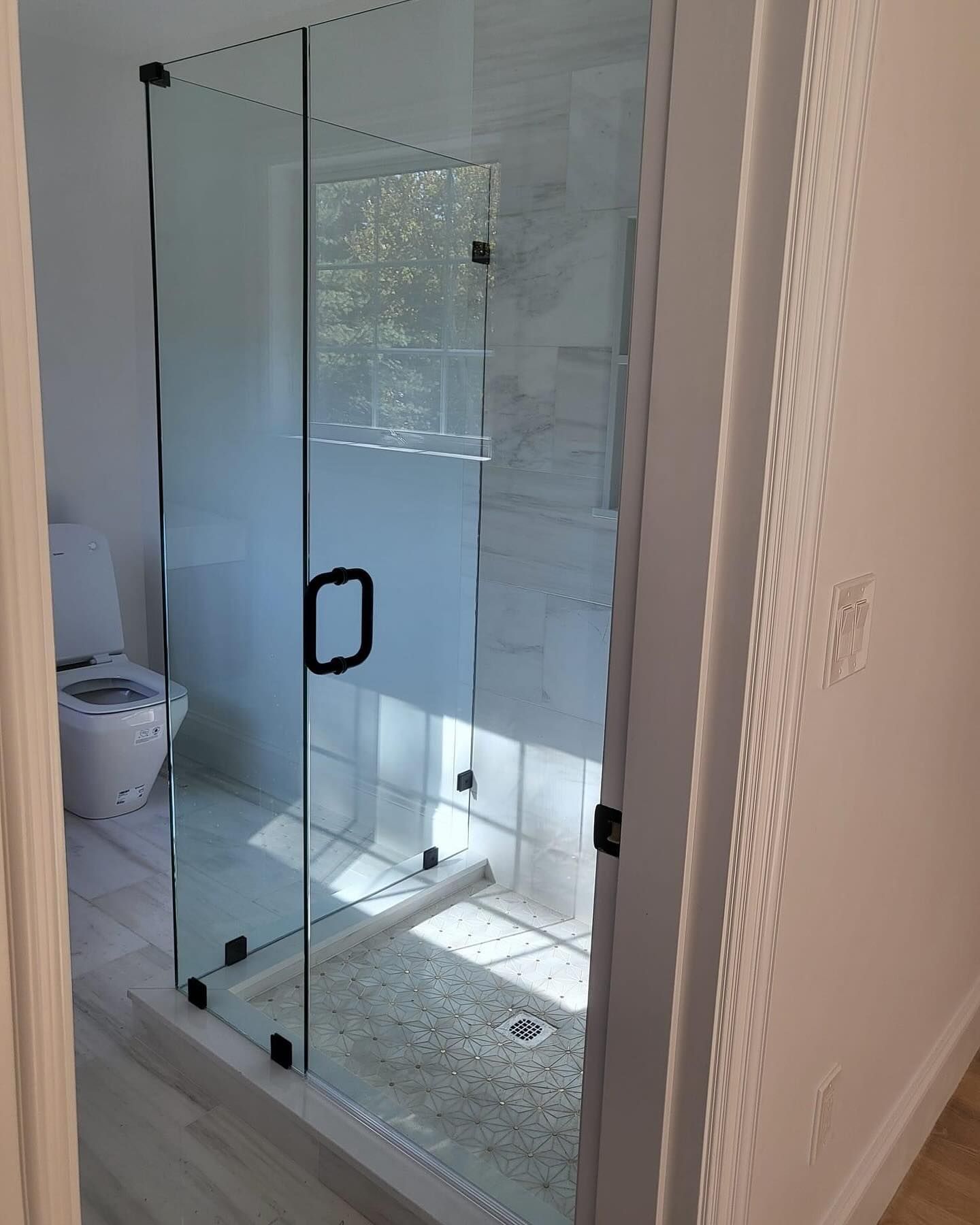 A bathroom with a glass shower door and a toilet.