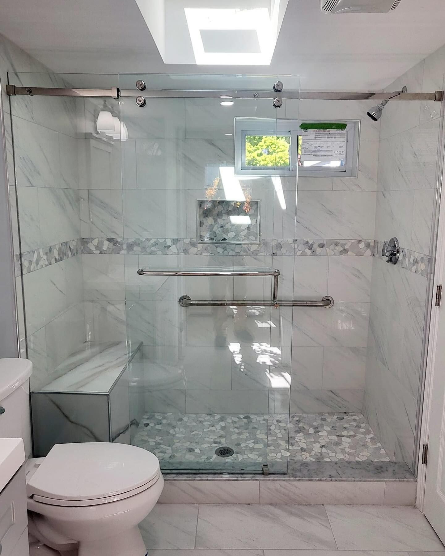 A bathroom with a toilet and a shower stall with a sliding glass door.