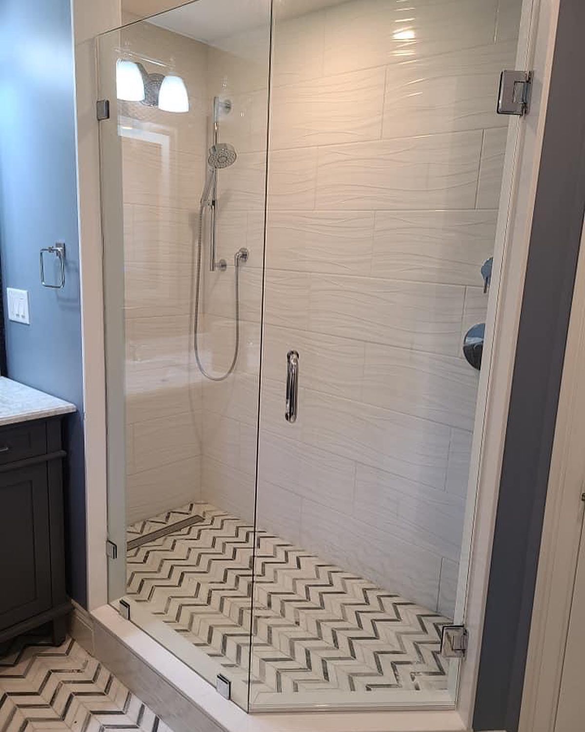 A bathroom with a walk in shower with a glass door.