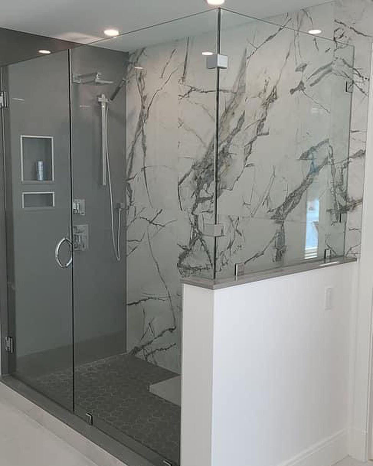 A bathroom with a walk in shower and a marble wall.