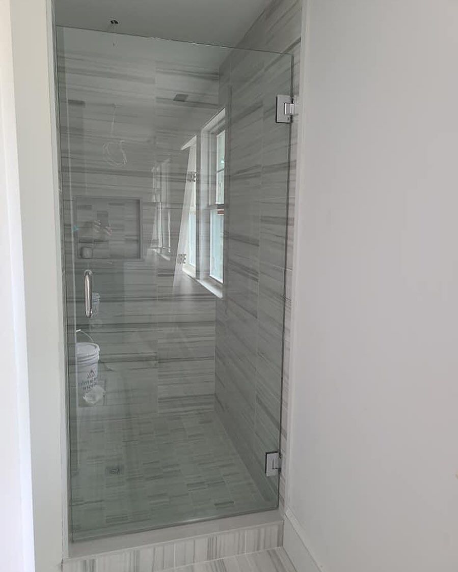 A bathroom with a glass shower door and a window.