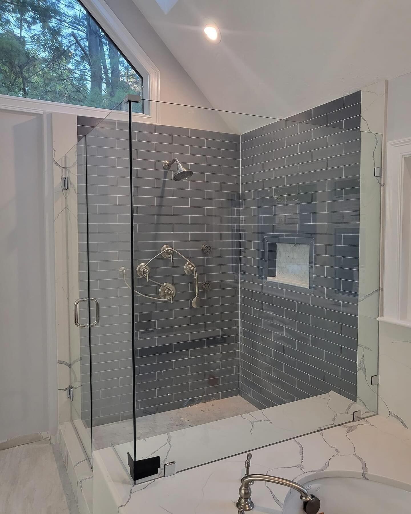 A bathroom with a walk in shower and a sink.