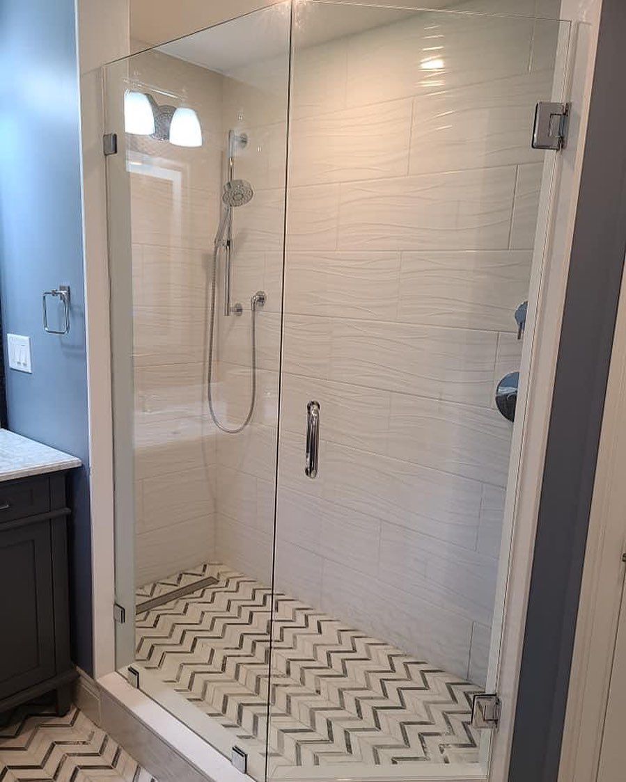 A bathroom with a walk in shower with a glass door.