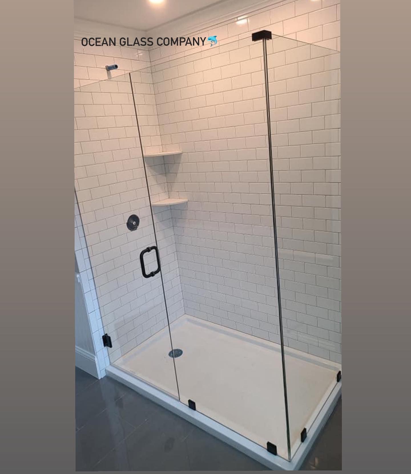 A shower stall with a glass door and white tile walls.