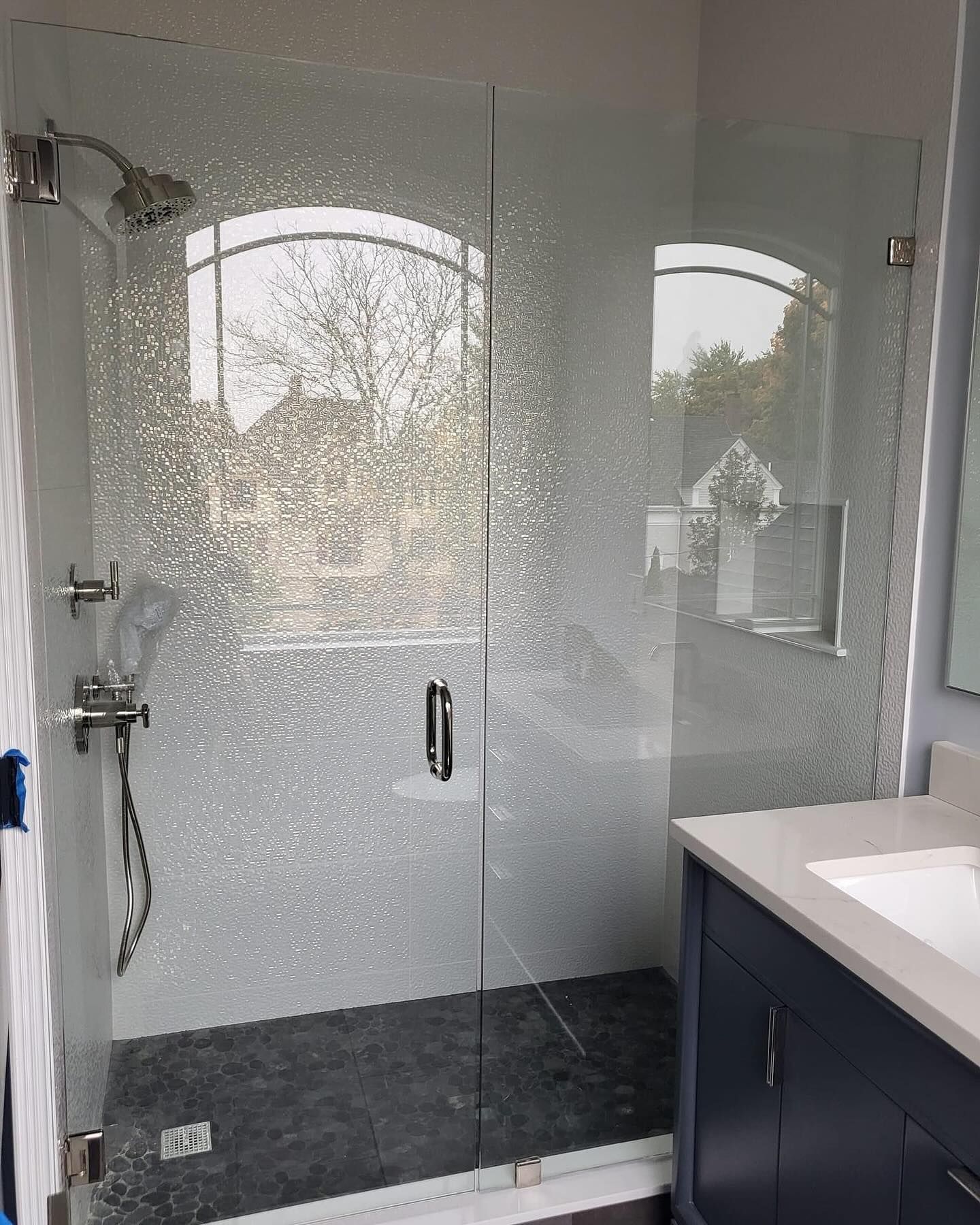 A bathroom with a walk in shower and a sink.