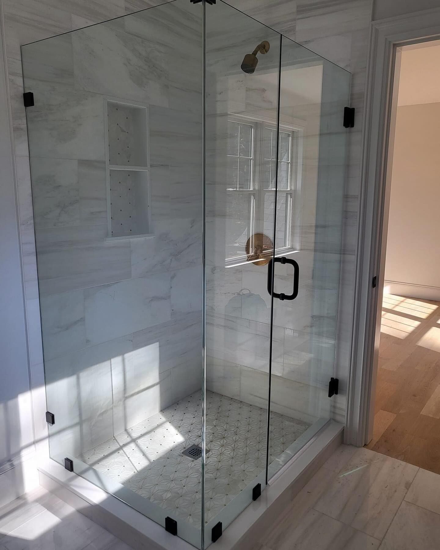 A bathroom with a walk in shower with a glass door.