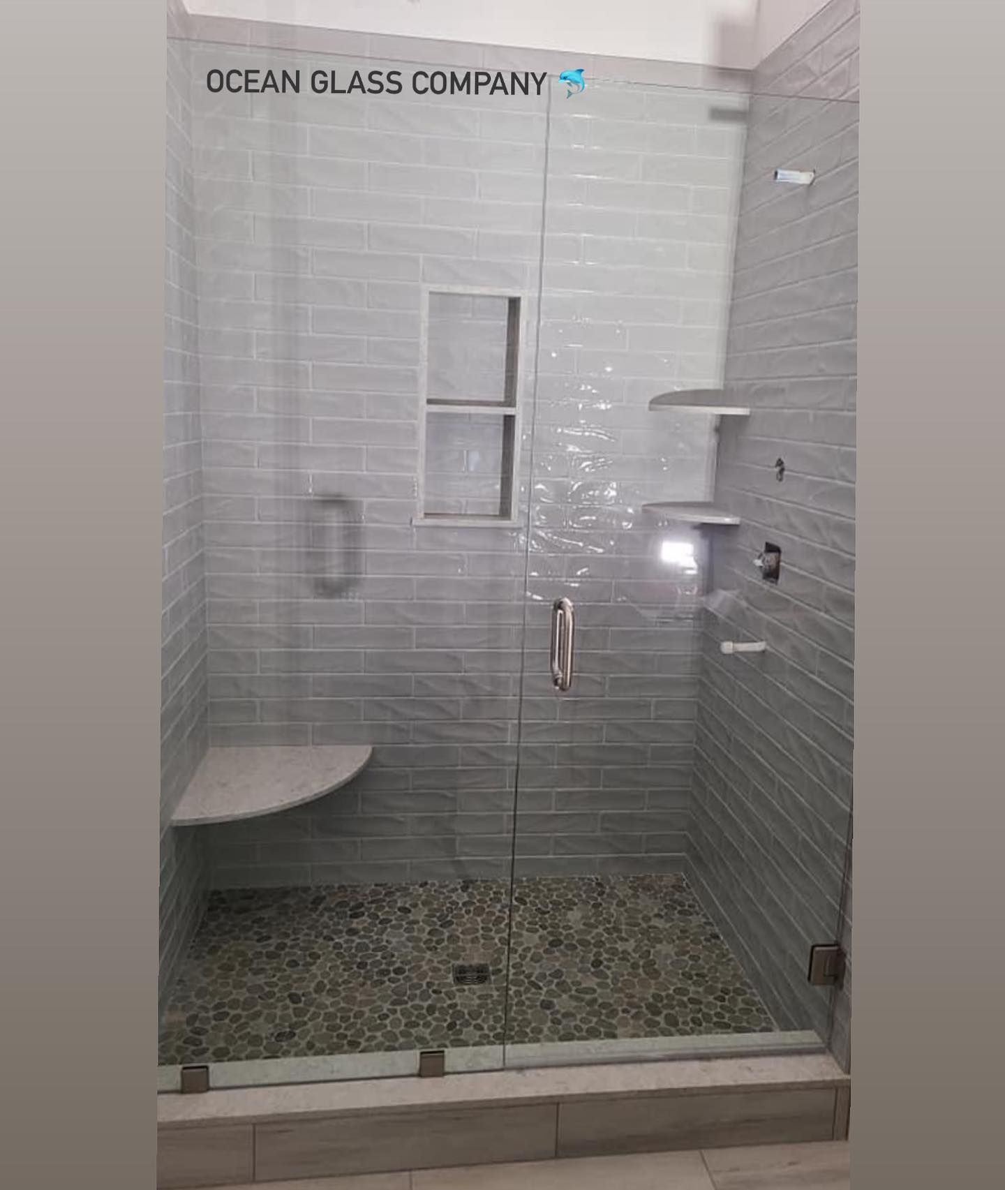 A bathroom with a glass shower door and a bench.