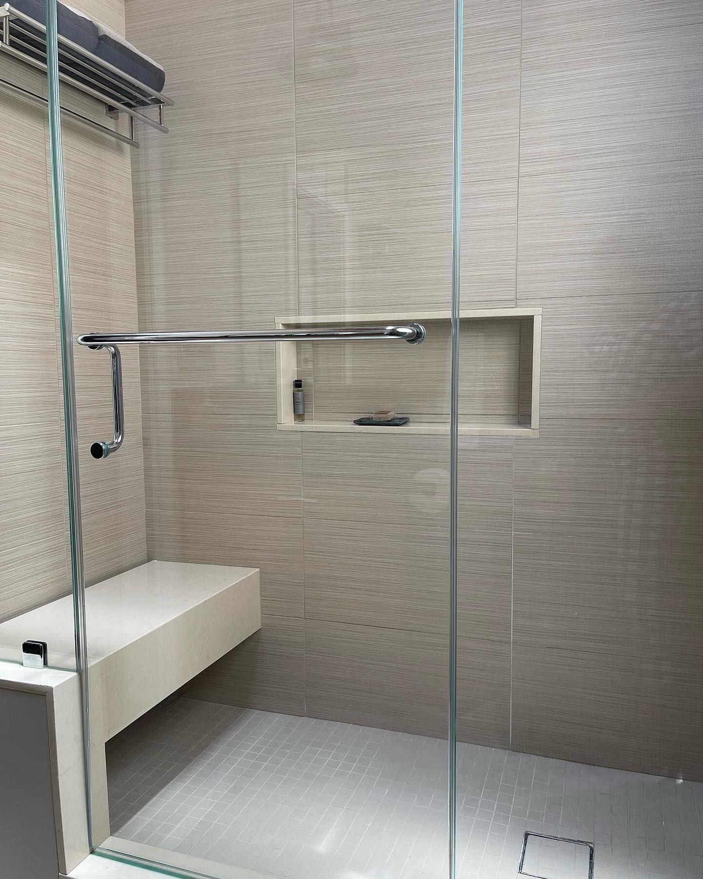 A bathroom with a walk in shower and a bench.