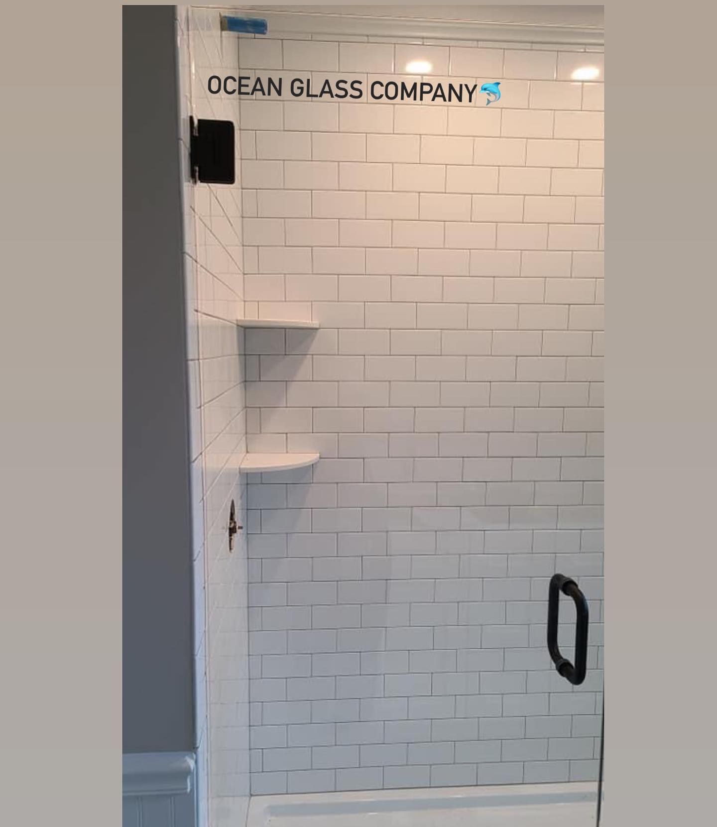 A bathroom with white subway tiles and a glass shower door.
