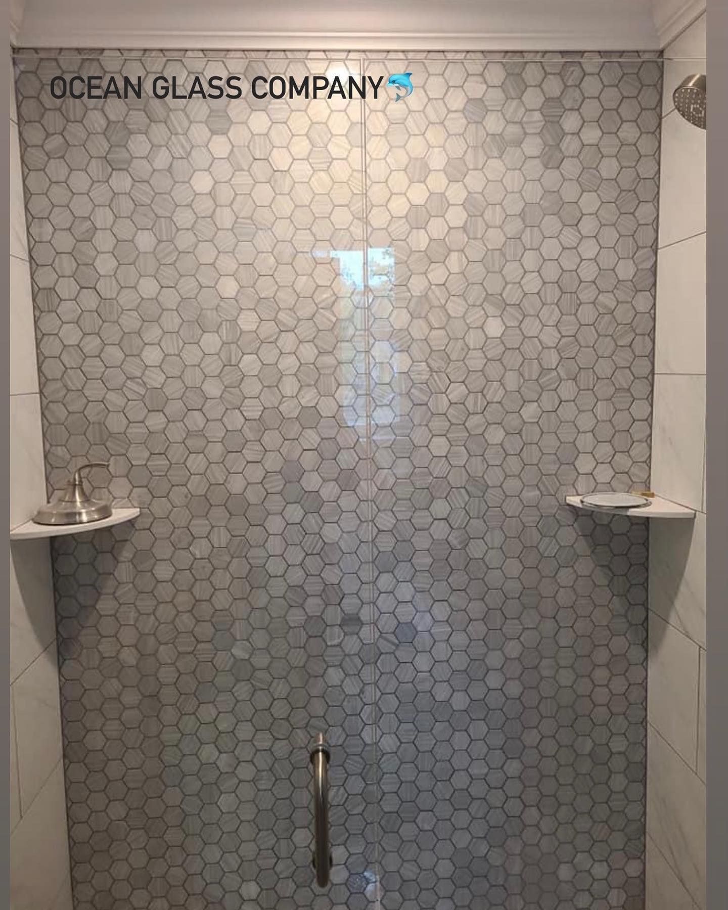 A shower with a glass door and a tiled wall.
