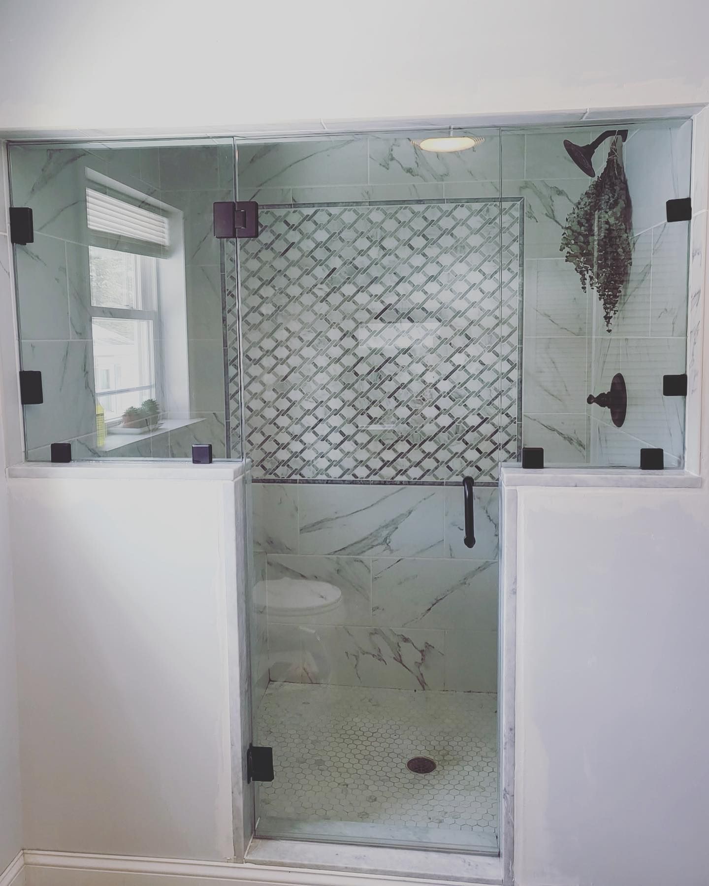 A bathroom with a walk in shower and a window.