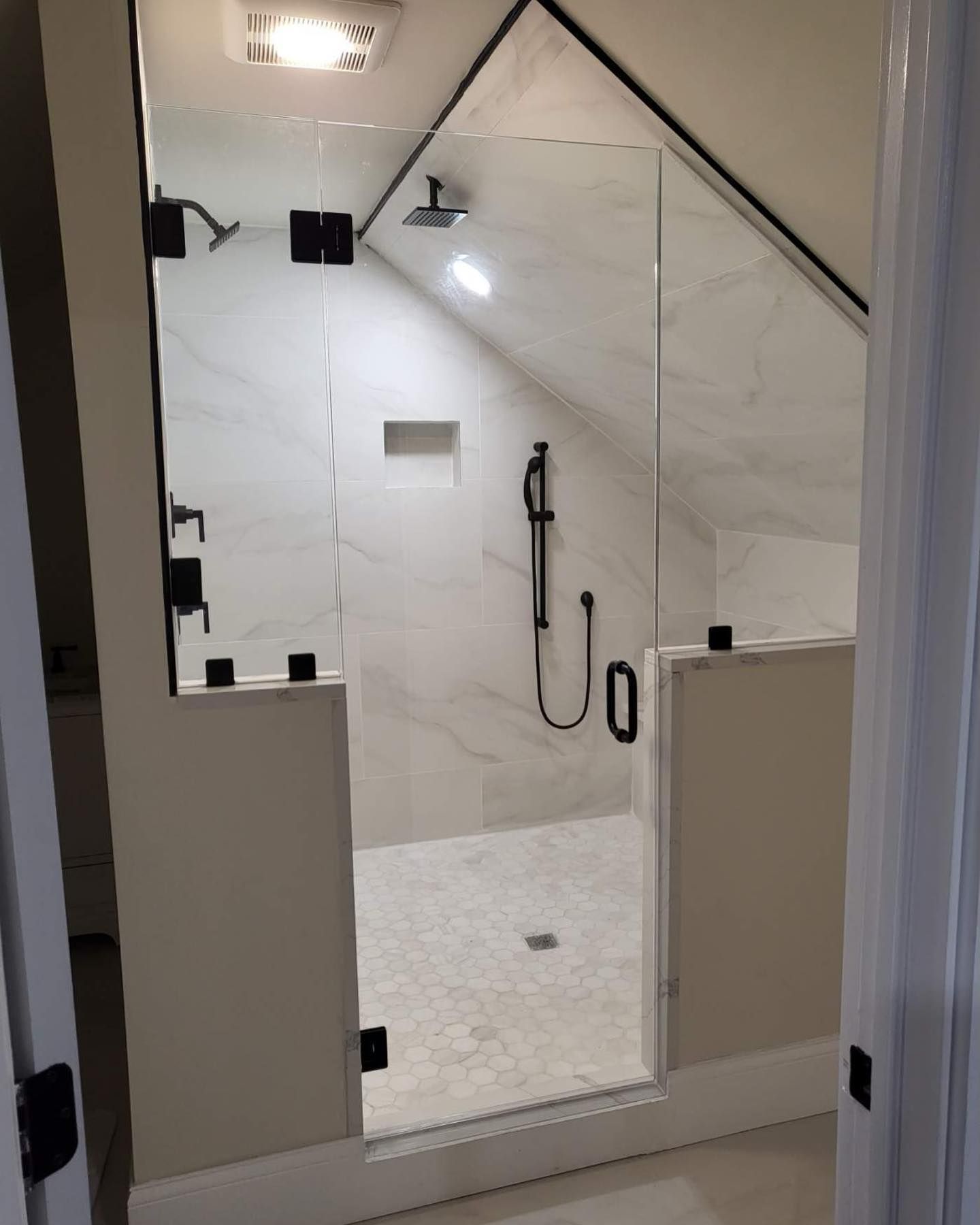 A bathroom with a walk in shower with a glass door.