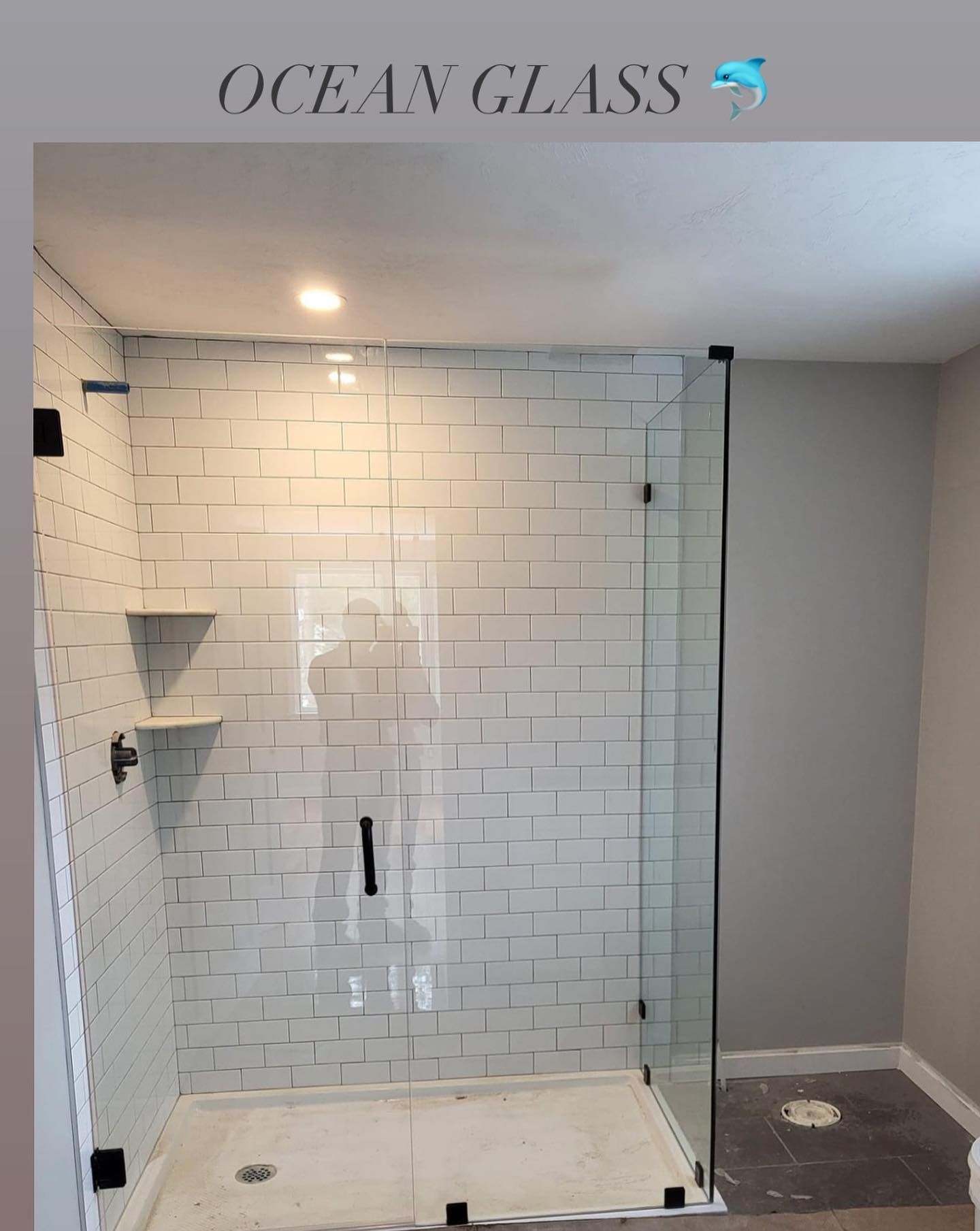 A bathroom with a shower stall and a sign that says ocean glass