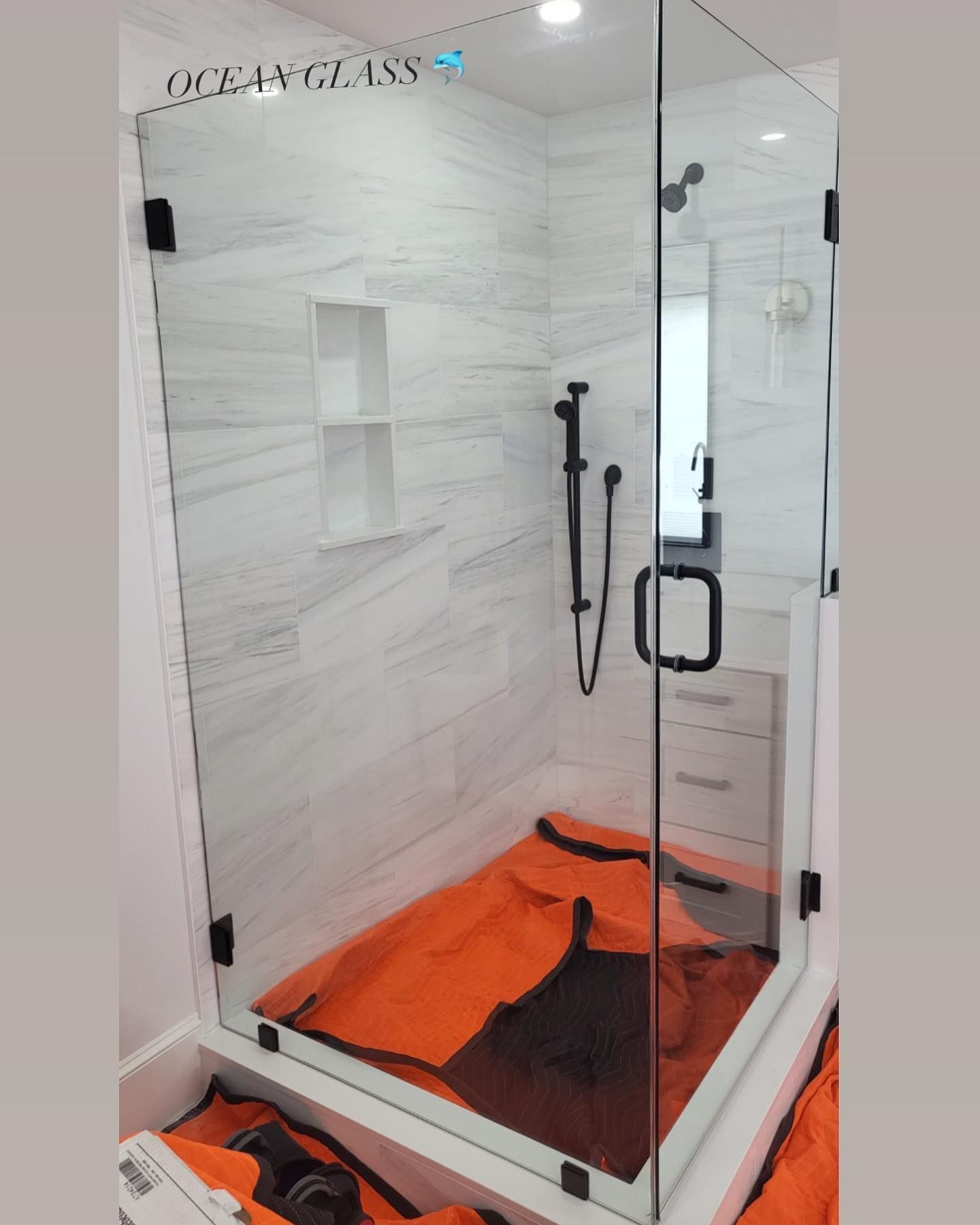 A bathroom with a shower stall and a bag on the floor.