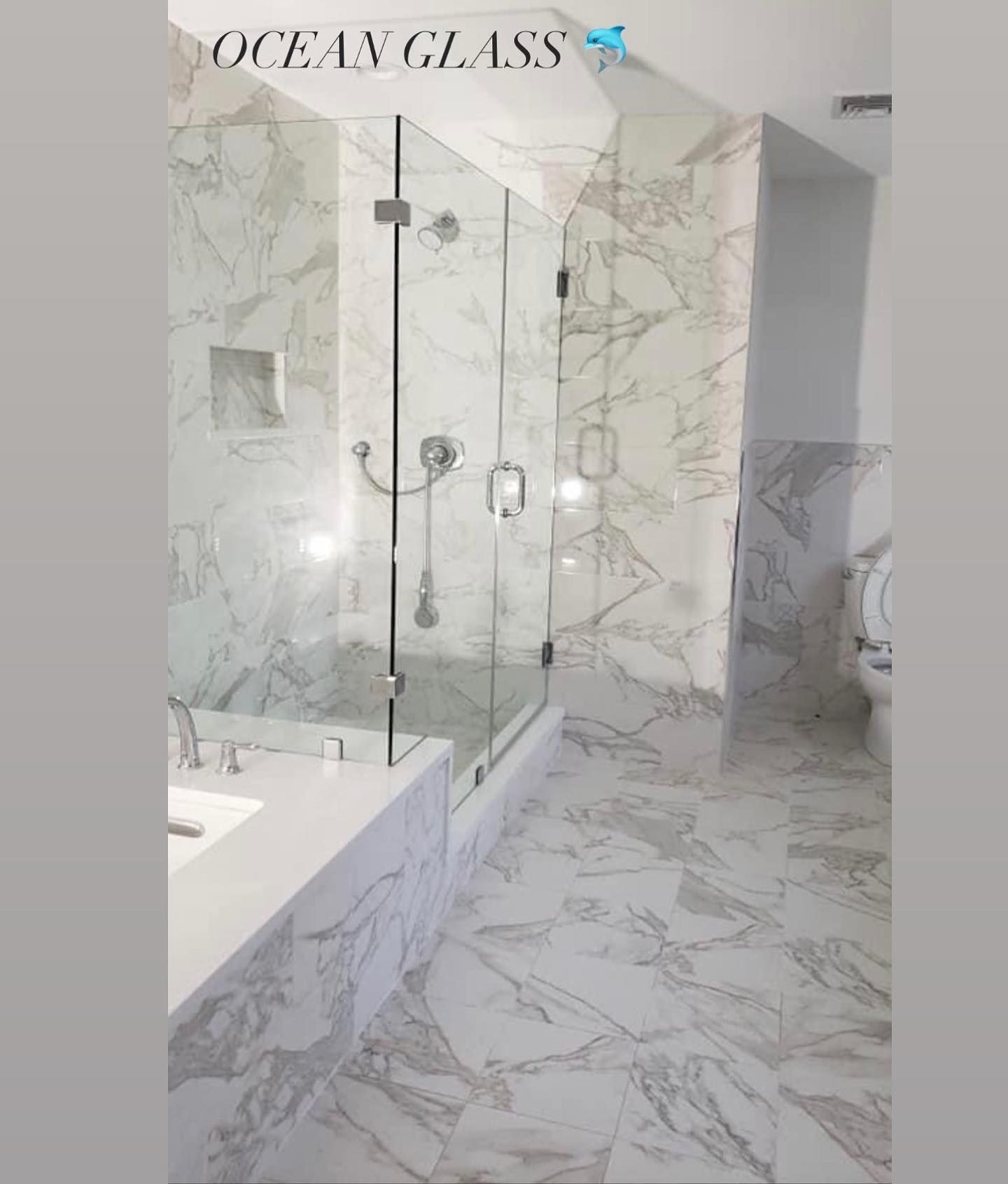 A bathroom with marble tiles and a walk in shower.