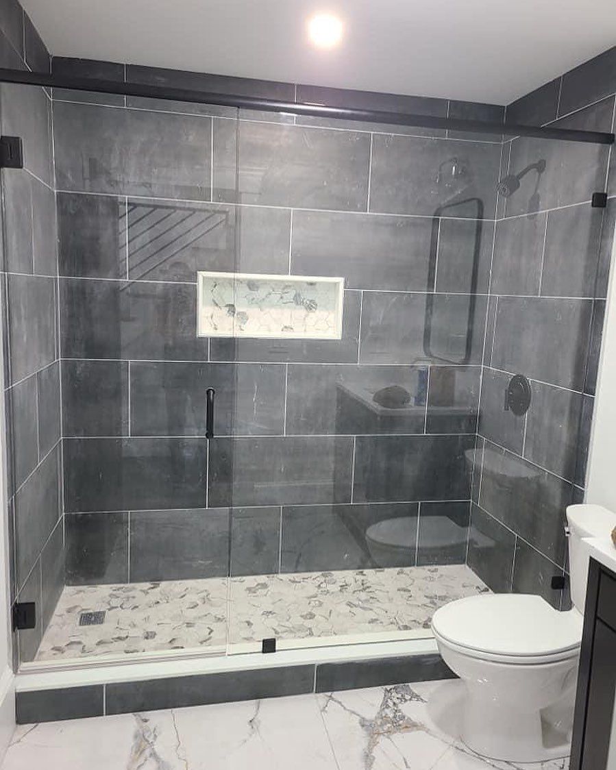 A bathroom with a toilet , sink , shower and glass door.