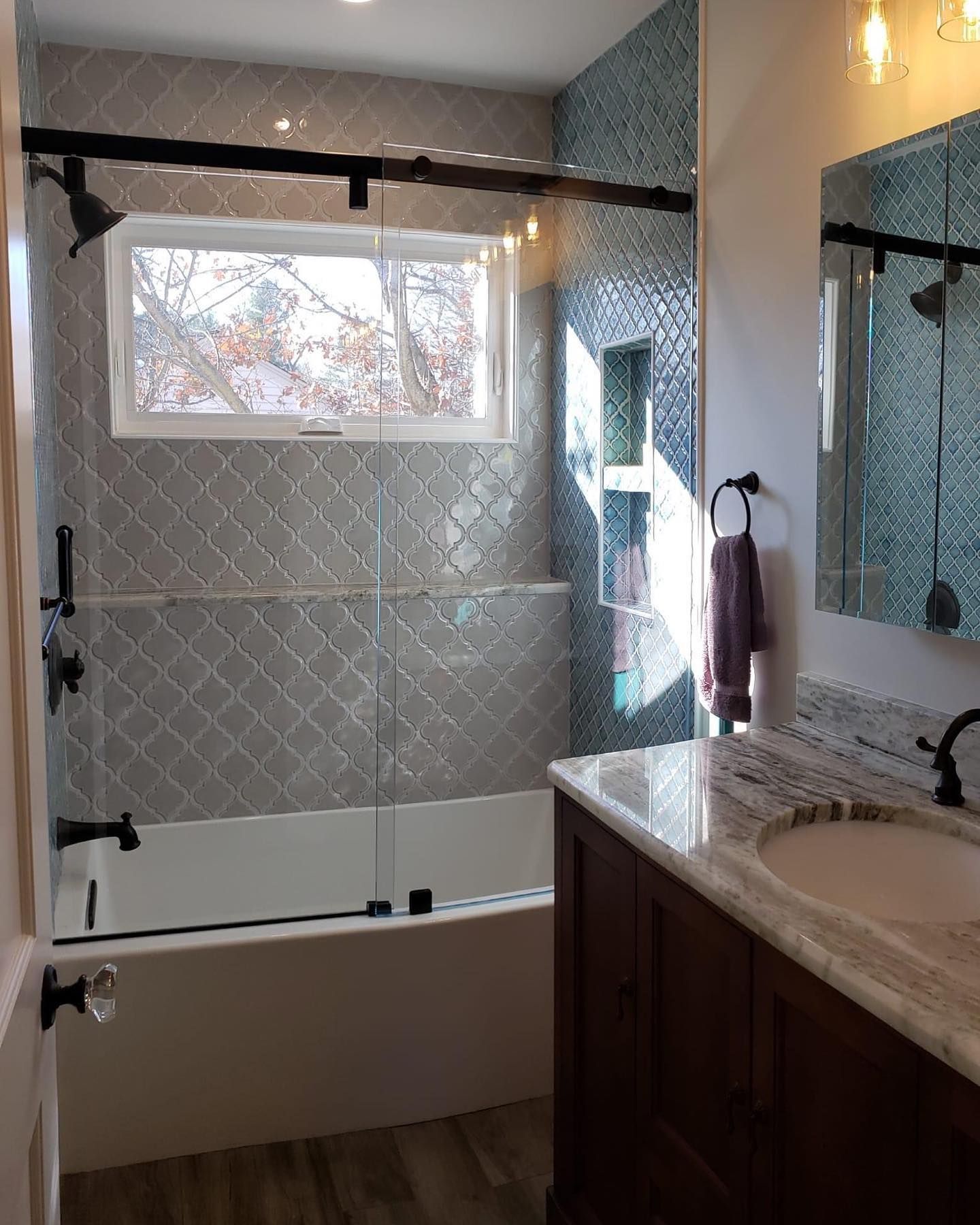 A bathroom with a tub , sink , mirror and shower.