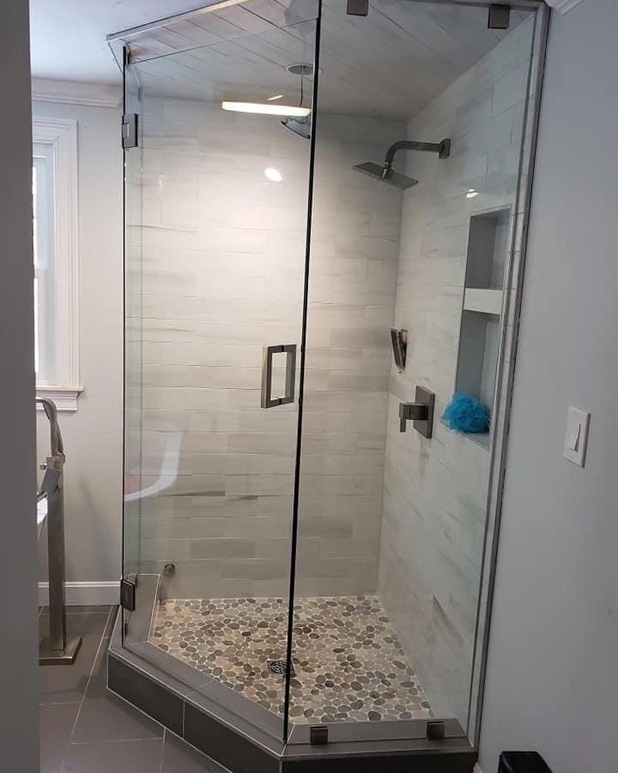 A bathroom with a walk in shower with a glass door.