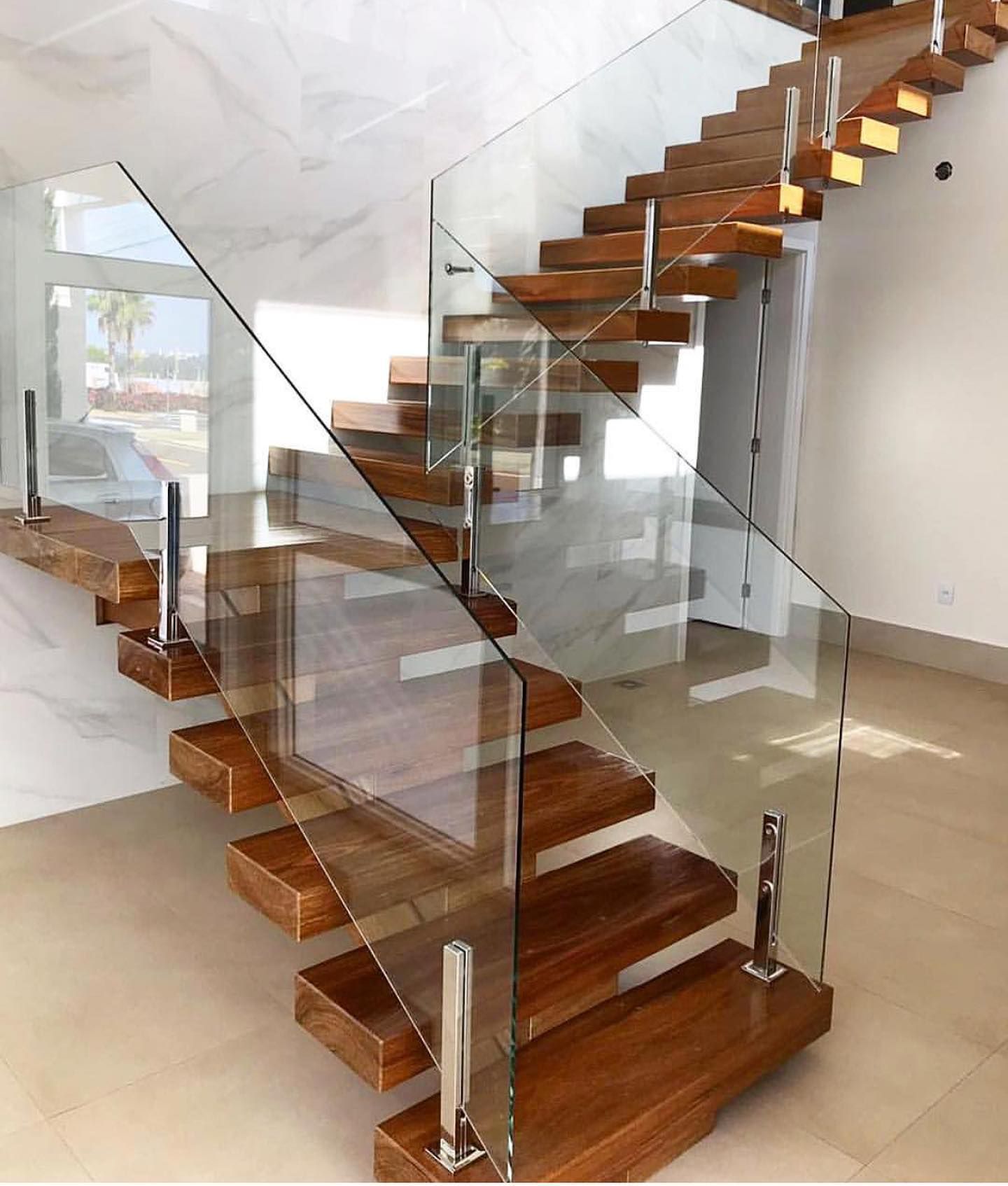 A wooden staircase with a glass railing in a room.