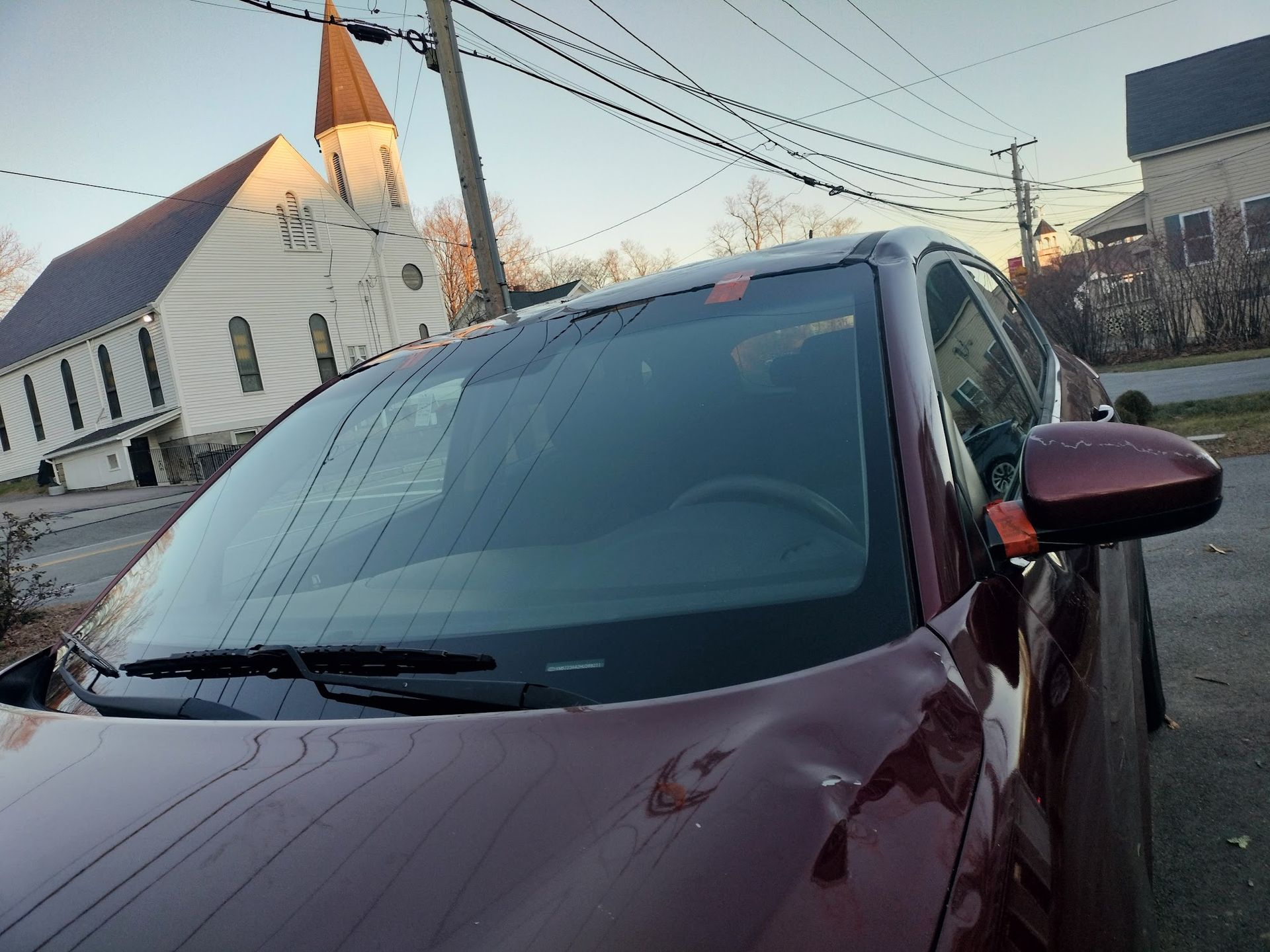 A red car is parked in front of a church