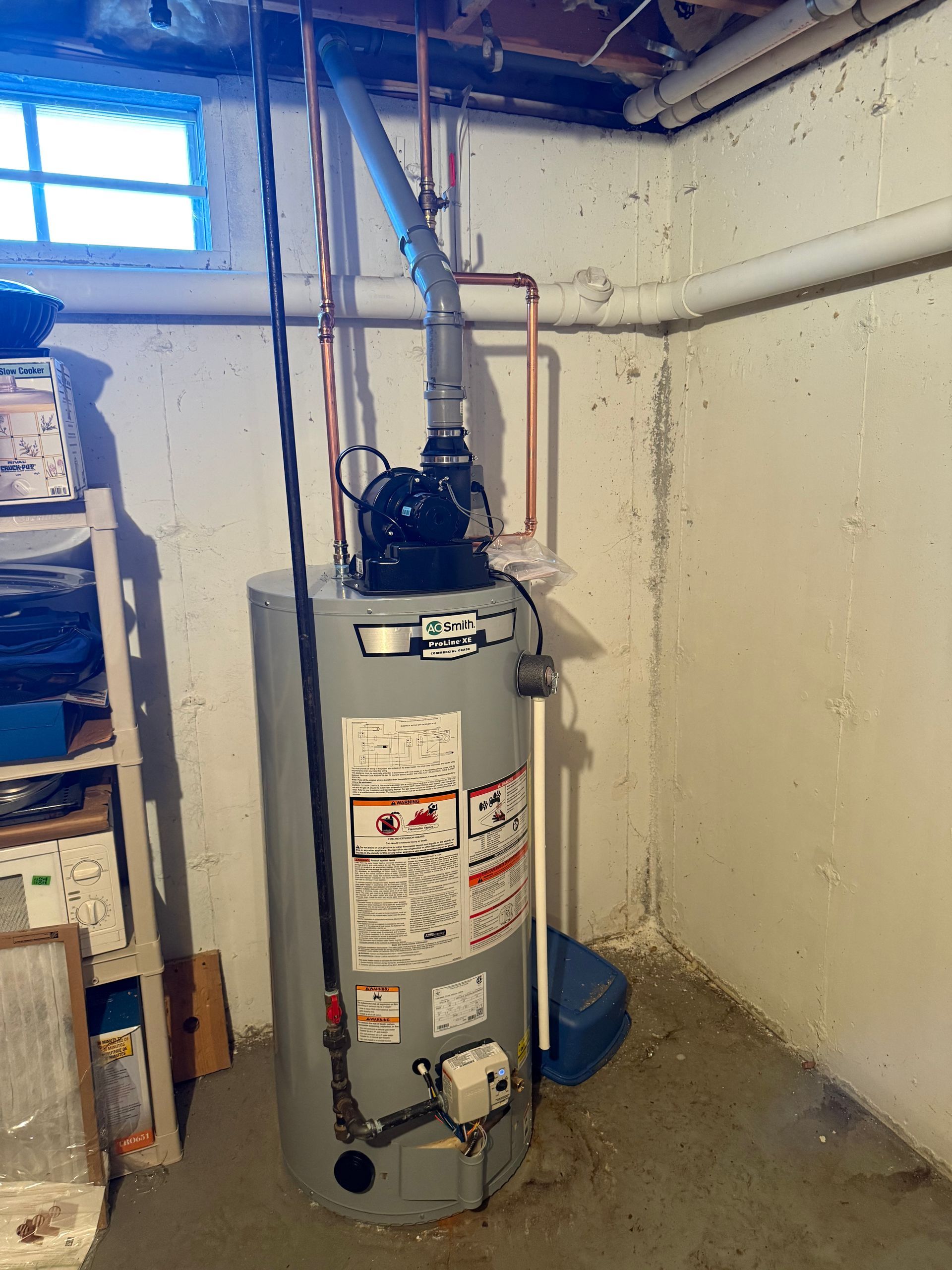 Water heater in a basement corner, with pipes and vent.